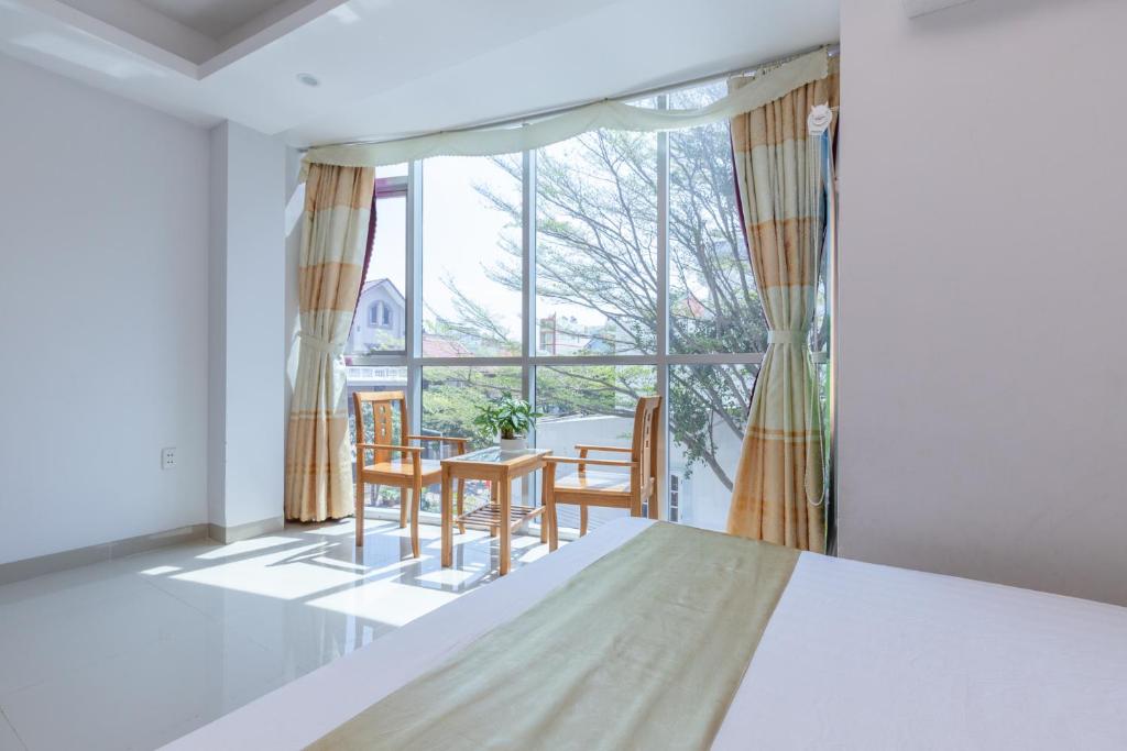 头顿RIO Hotel and Apartment的客房设有桌椅和大窗户。
