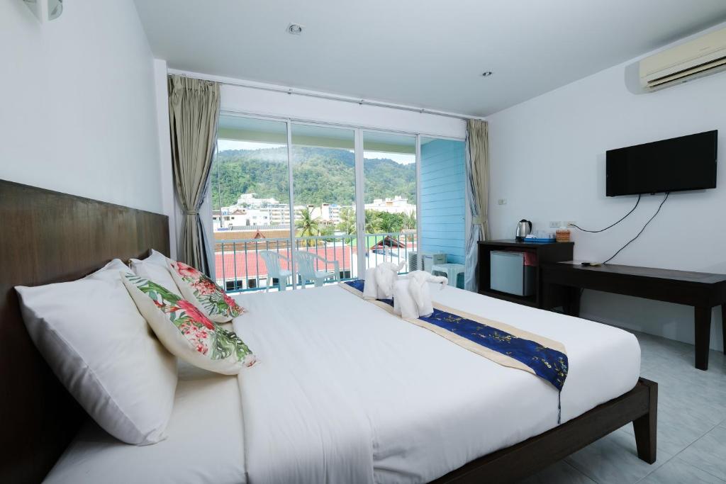 芭东海滩Kiwi Boutique Hotel的卧室配有一张大白色床和窗户