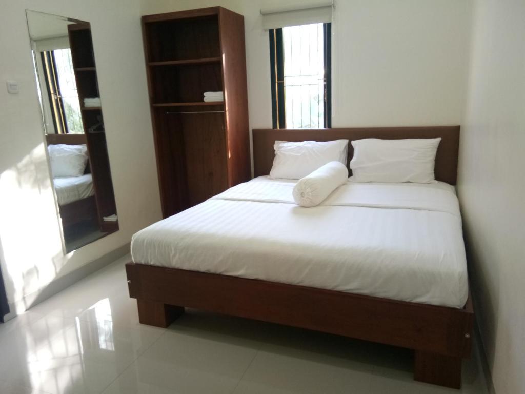 安汶Clean & Comfort Homestay的一间卧室配有带白色床单和枕头的床。