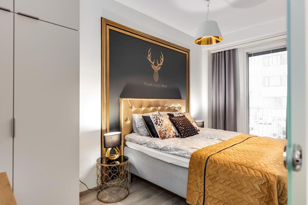 奥卢Trendy Homes Oulu Marski Apartments的一间卧室配有一张特大号床和金色床头板