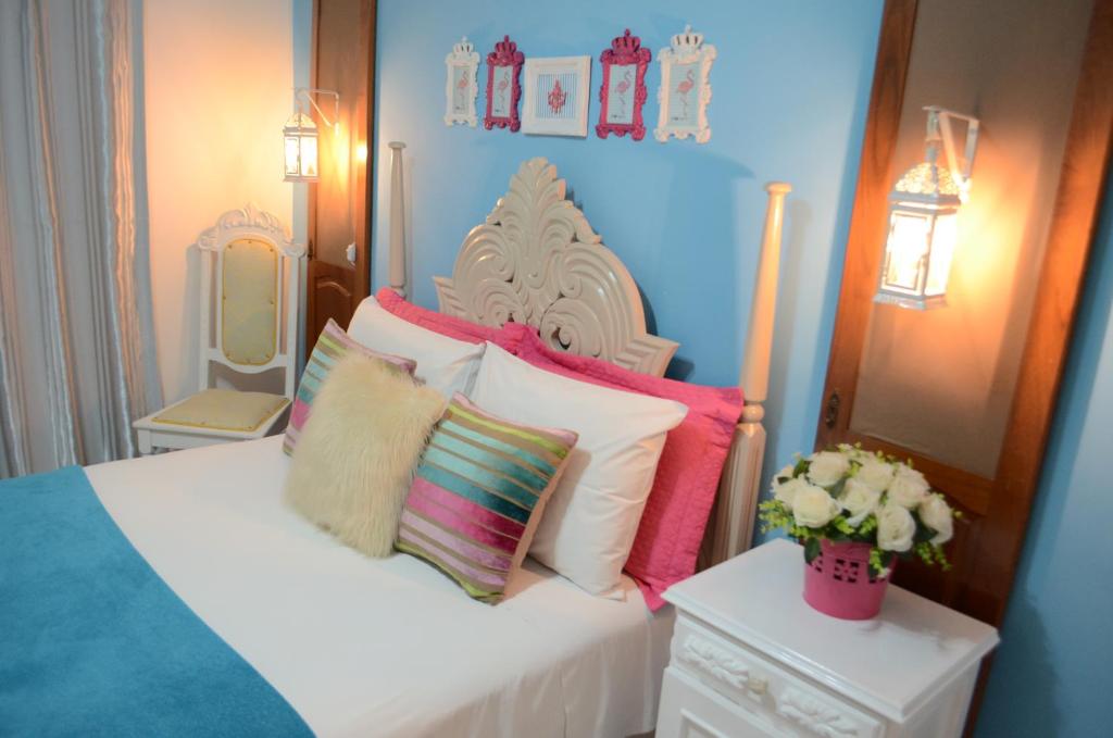 伊瓜苏La Maison Brasiliana B&B的卧室配有白色的床和色彩缤纷的枕头
