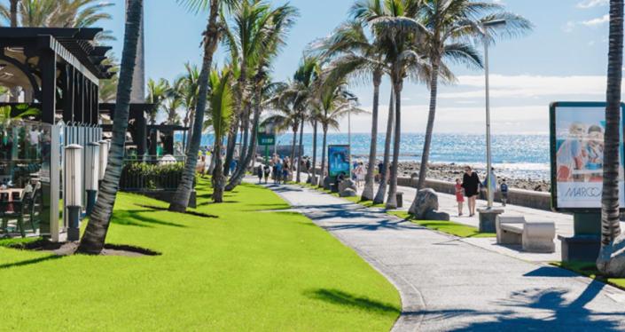 圣巴托洛梅Villa Meloneras - Exclusive Chill Out的海滨人行道,毗邻棕榈树和大海的海滩