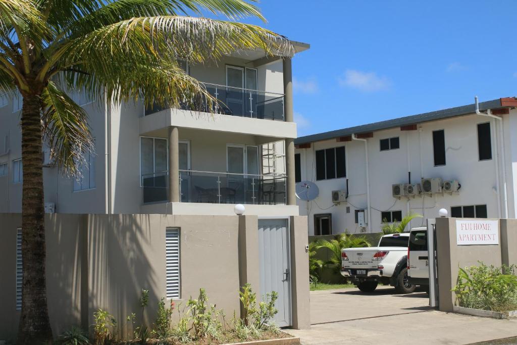 苏瓦FIJI HOME Apartment Hotel的停车场旁的棕榈树建筑