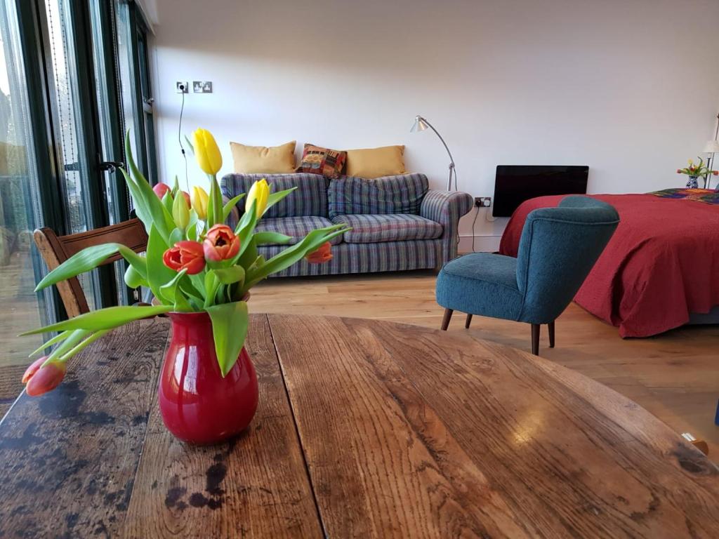 ThreshfieldThe Sett on The Wharfe的客厅里的一个红色花瓶,上面有鲜花