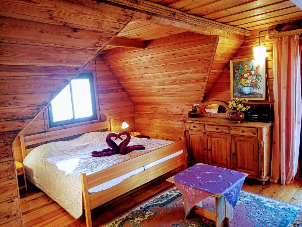希维拉杜夫-兹德鲁伊Sępia Chata Dom Do Wynajęcia的一间卧室配有一张带紫色丝带的床