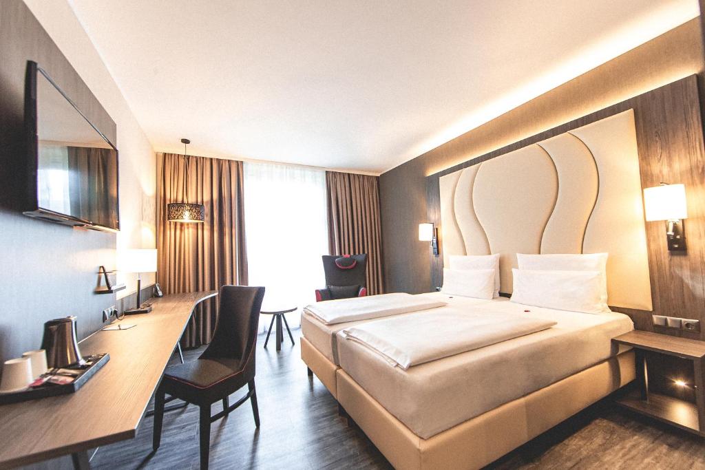 诺德施泰特PLAZA Premium Parkhotel Norderstedt的配有一张床和一张书桌的酒店客房