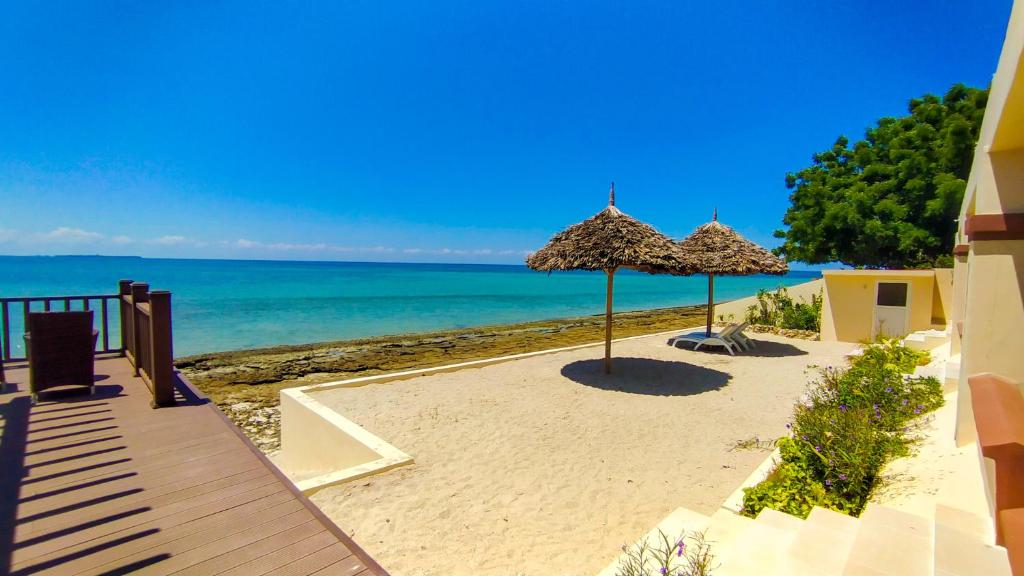 桑给巴尔Golden Palm Boutique Zanzibar的海滩上有两个遮阳伞和大海