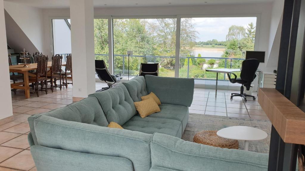 诺伊斯Somnar Panoramaloft mit Hästens Betten - Rheinblick 150qm的客厅设有蓝色的沙发和大窗户