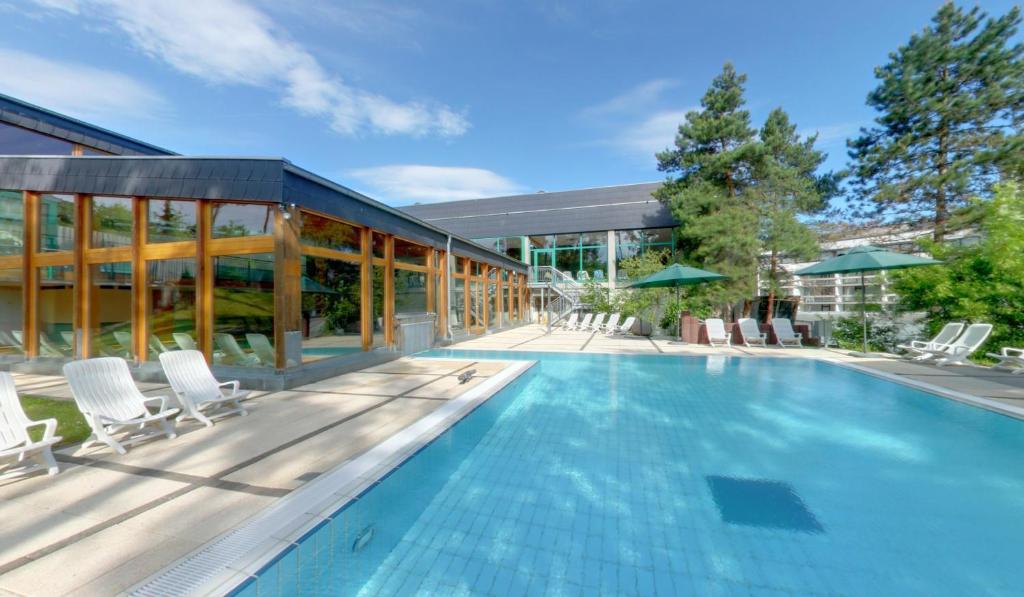 巴特基辛根索奈胡格酒店的一座带椅子的游泳池以及一座建筑