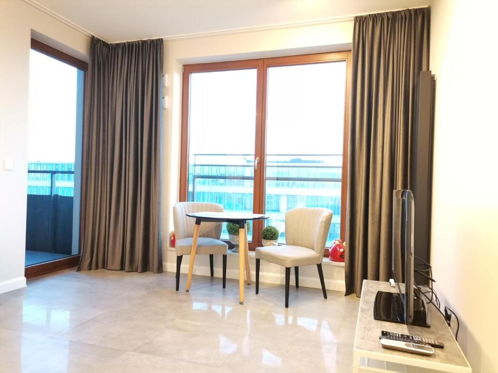 华沙Luxusowy Apartament Klimczaka的客厅配有桌椅和窗户。