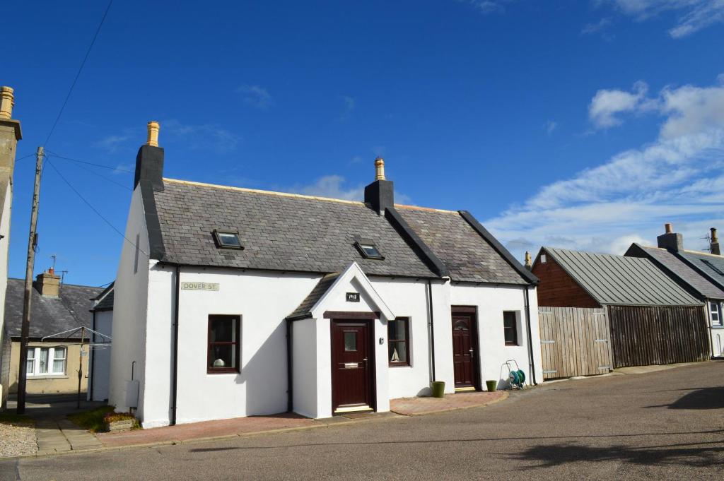 Portknockie4-Bed Cottage in Portknockie Near Cullen Moray的一条白色的街道上,有黑色屋顶