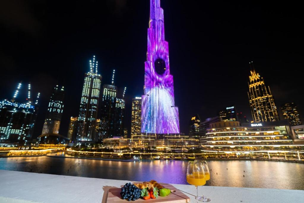 迪拜Durrani Homes - Heaven On Earth- Burj Khalifa Fireworks的一张桌子,上面放着一盘食物和一杯葡萄酒