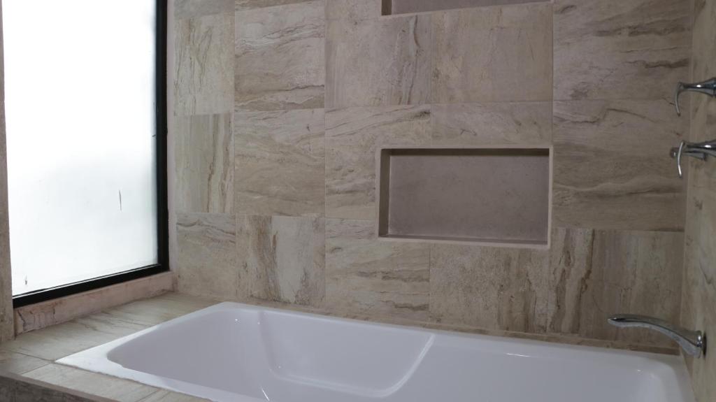 科巴Hotel Itza Coba的带浴缸的浴室和石墙