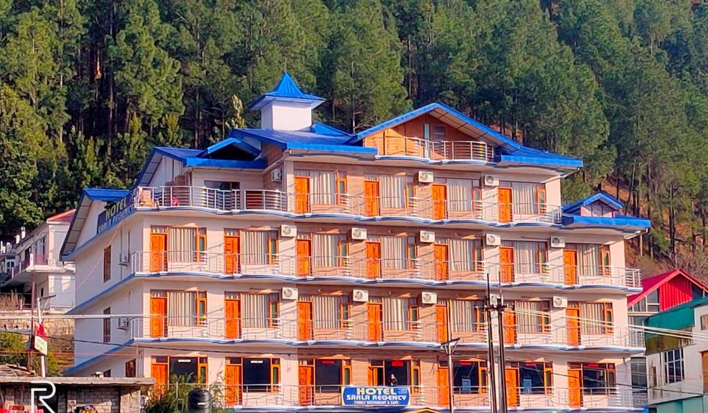库尔卢Hotel Sarla Regency的一座拥有橙色和蓝色屋顶的大型建筑