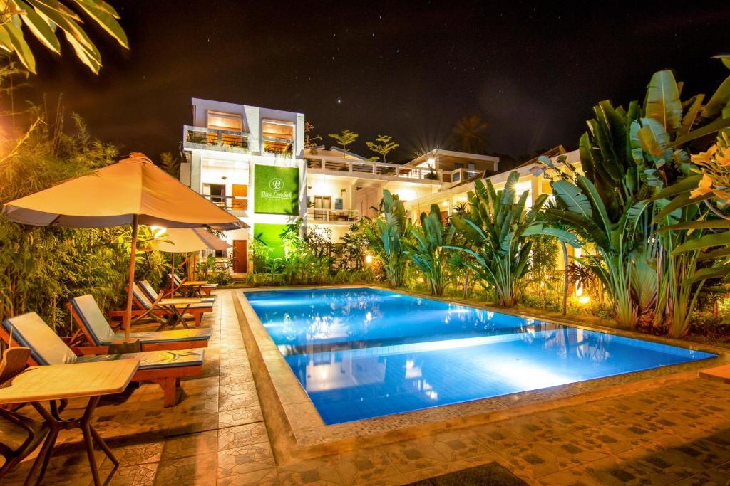 圣吉吉Diva Lombok Resort的游泳池在晚上配有桌椅