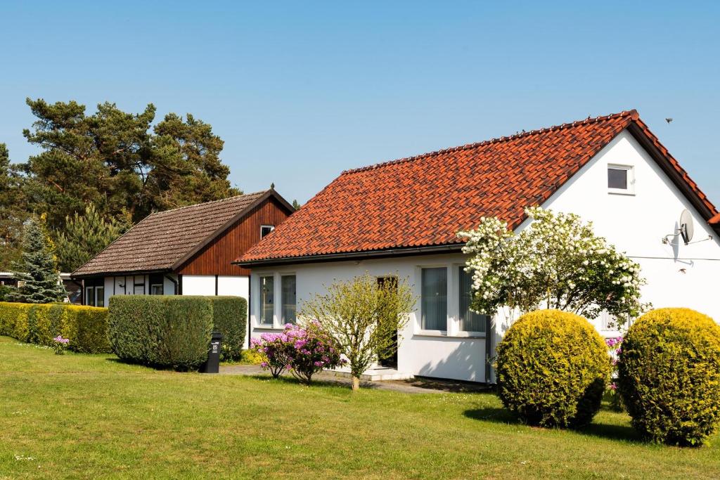 富伦多夫Holiday home Fuhlendorf 1的白色的房子,有红色的屋顶和灌木