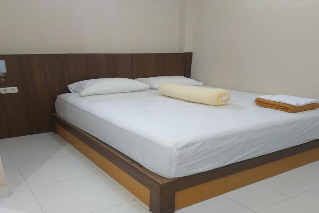 帕卢Nietsa Guest House Syariah Palu Mitra RedDoorz的一张带白色床单的床和两个枕头