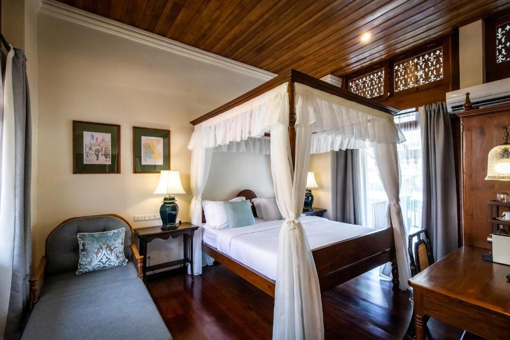 尖竹汶Punyashthiti villa的一间卧室配有一张天蓬床和一把椅子