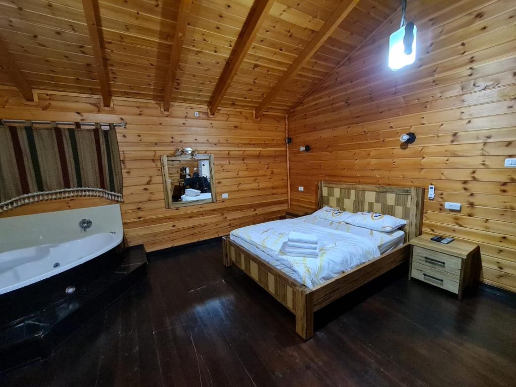 谢莫纳城בקתות היובל的木制客房设有一间带一张床和一个浴缸的卧室
