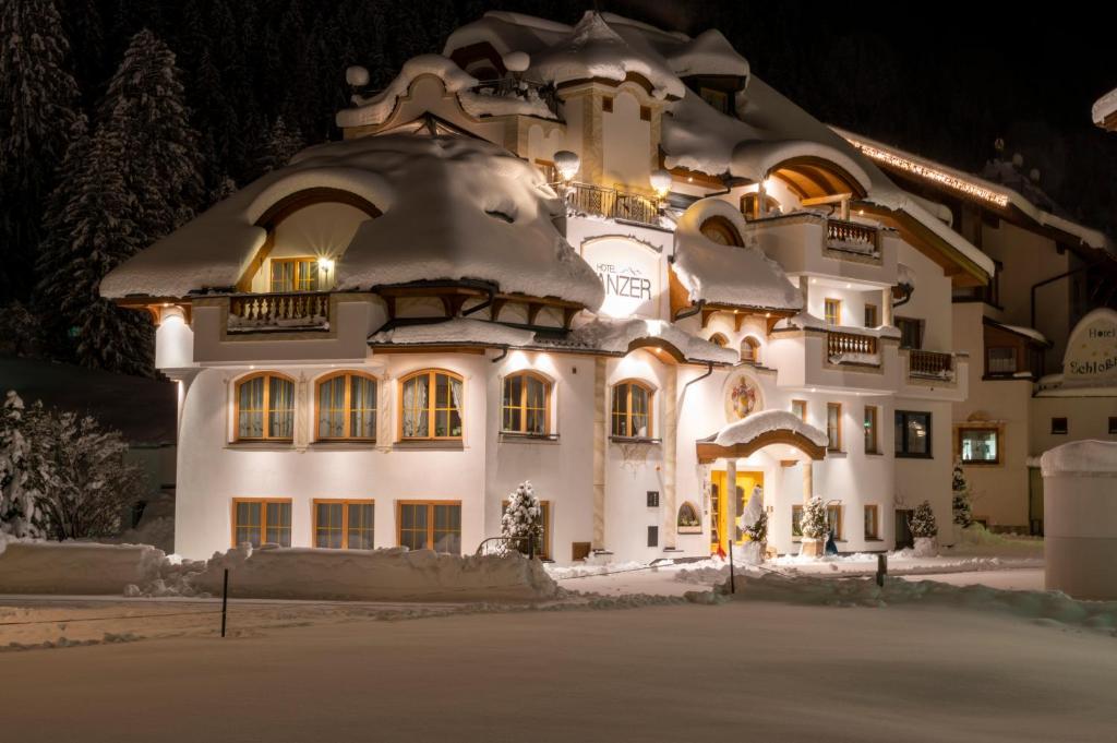 伊施格尔Hotel Tanzer的一座白色的大建筑,有雪盖屋顶