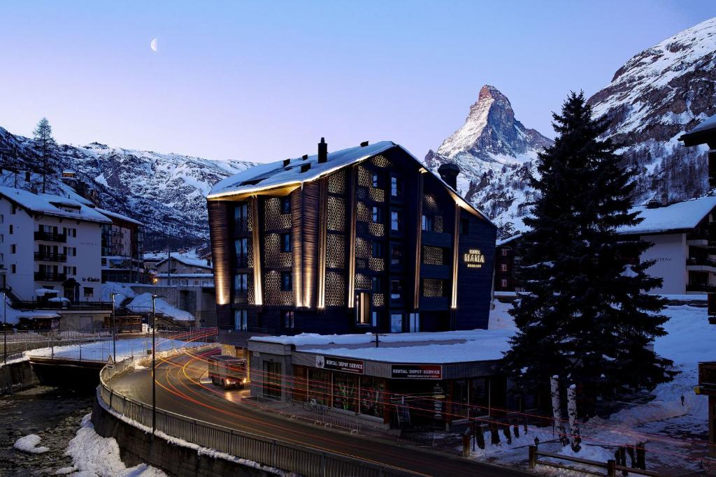 采尔马特Hotel ZERMAMA Zermatt的山前的积雪建筑