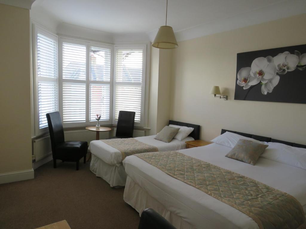伦敦马普尔住宿加早餐旅馆的酒店客房带两张床和一张桌子以及椅子。