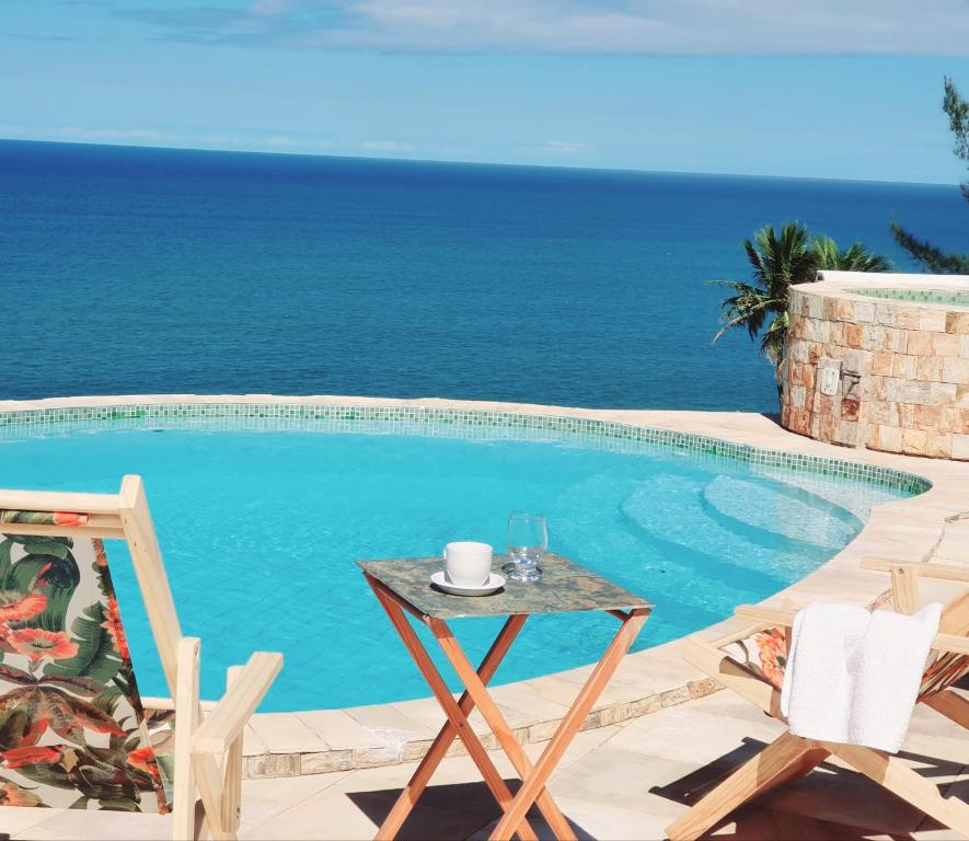马里卡Casa do Maracuja的毗邻大海的带桌椅的游泳池