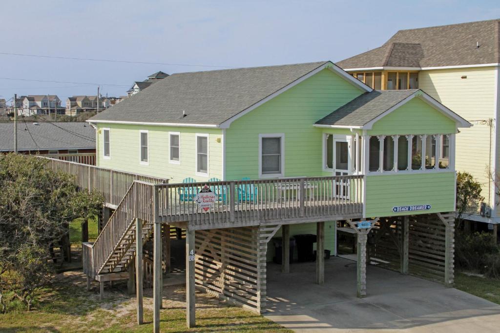 巴克斯顿Beach Dreamer #4-BB的一座绿色房子,房子前设有木甲板