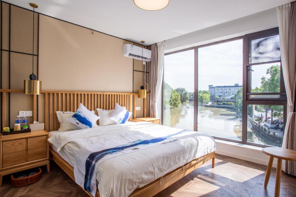 苏州同里泊·晓烟河景民宿的一间卧室设有一张大床和一个大窗户