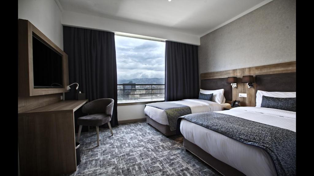 贝鲁特Hotel De Ville的酒店客房设有两张床和窗户。