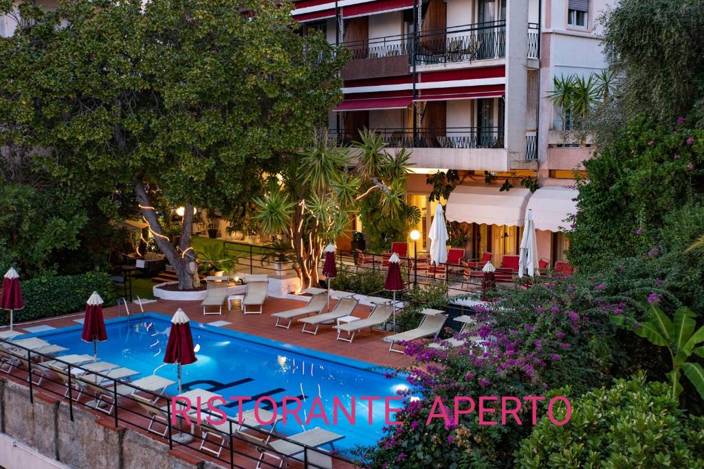 圣雷莫王子酒店的酒店旁的游泳池配有椅子和遮阳伞