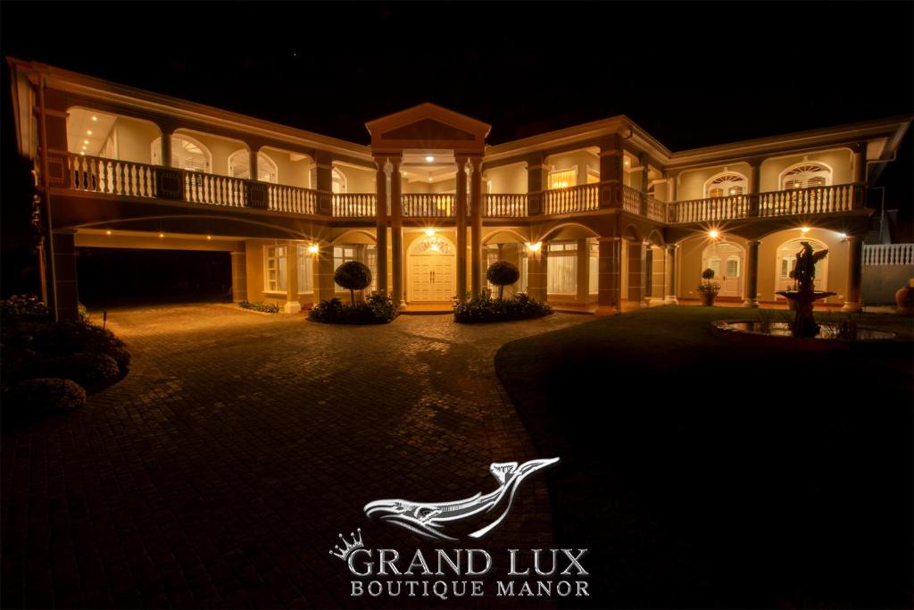 赫曼努斯Grand Lux Boutique Manor的一座大型的大厦,晚上有标志,上面写着豪华精品经理