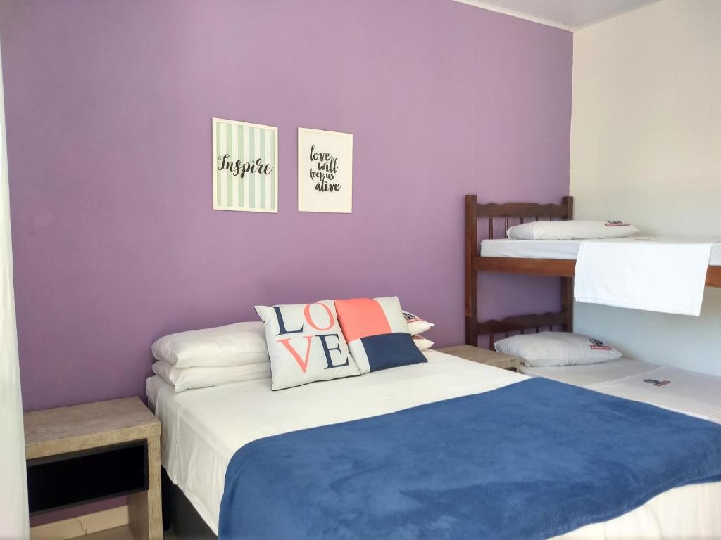 特拉曼达伊Pousada No Farol的一间卧室设有两张床和紫色墙壁