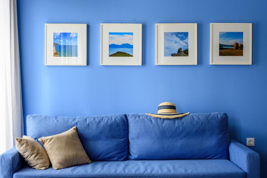 伊罗达Elounda Colour Apartments的蓝色沙发,靠着蓝色的墙壁,有四张照片
