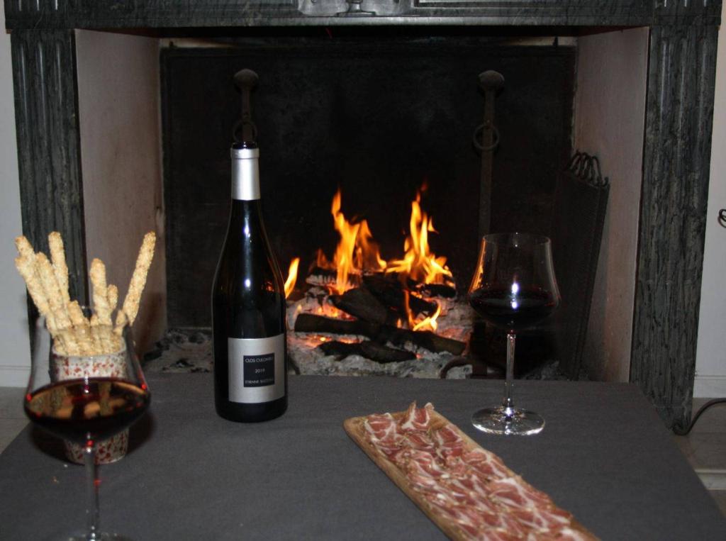 科尔巴拉Casa Di Angeli的壁炉桌子上放有一瓶葡萄酒和两杯酒