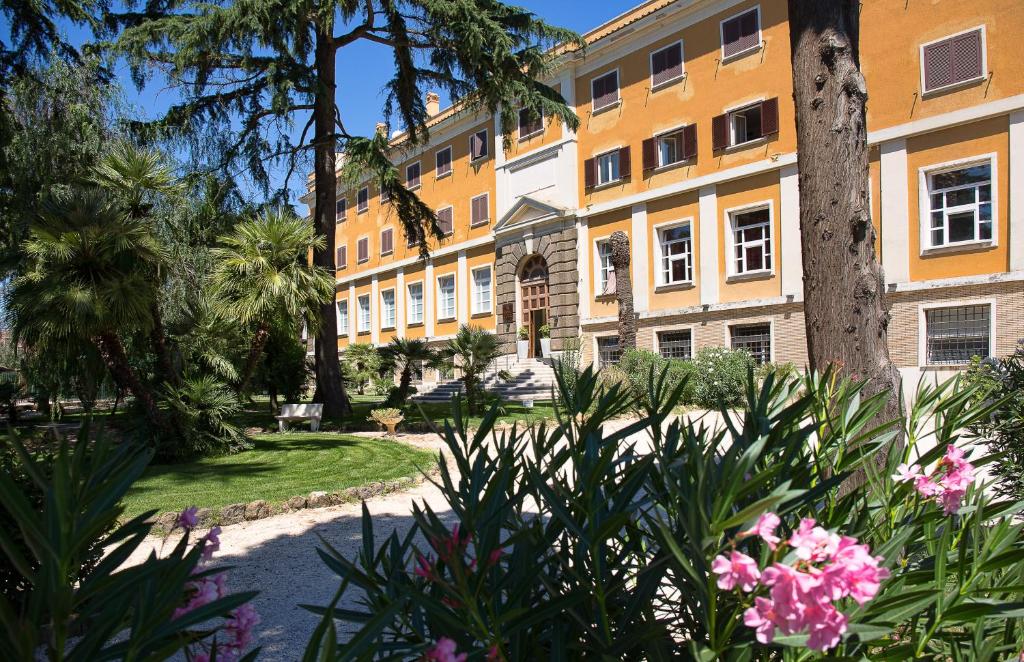 罗马Excel Roma Montemario的公园里种有棕榈树和鲜花的建筑