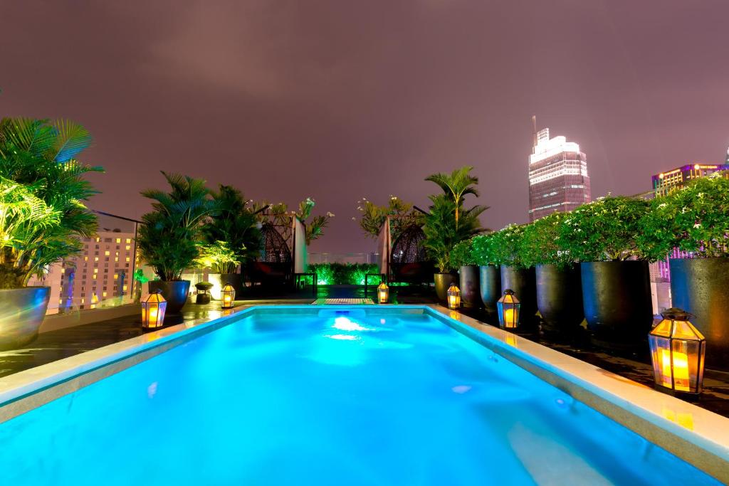 胡志明市Roseland Sweet Hotel & Spa的一座游泳池,在晚上在一座建筑的顶部