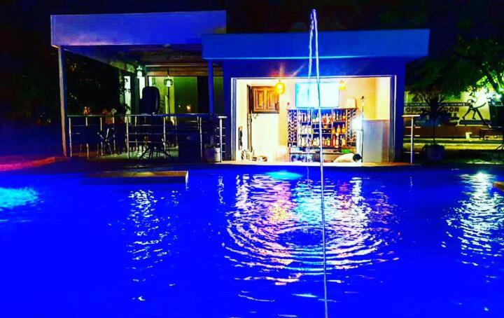 卢萨卡THE ESCAPE LODGE的一座房子前方的蓝色灯光游泳池