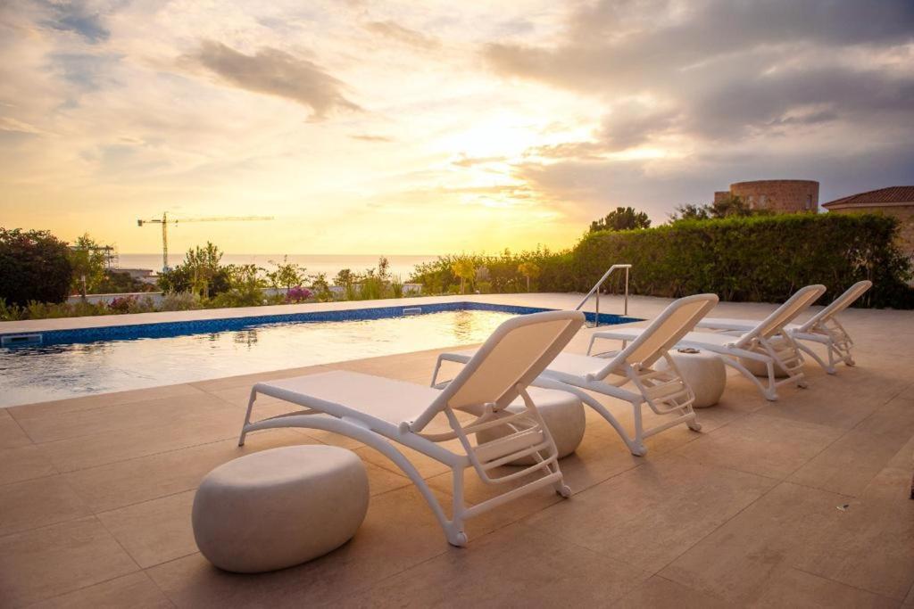 佩亚Villa No 1 - Cap St Georges Resort的一组椅子坐在游泳池旁