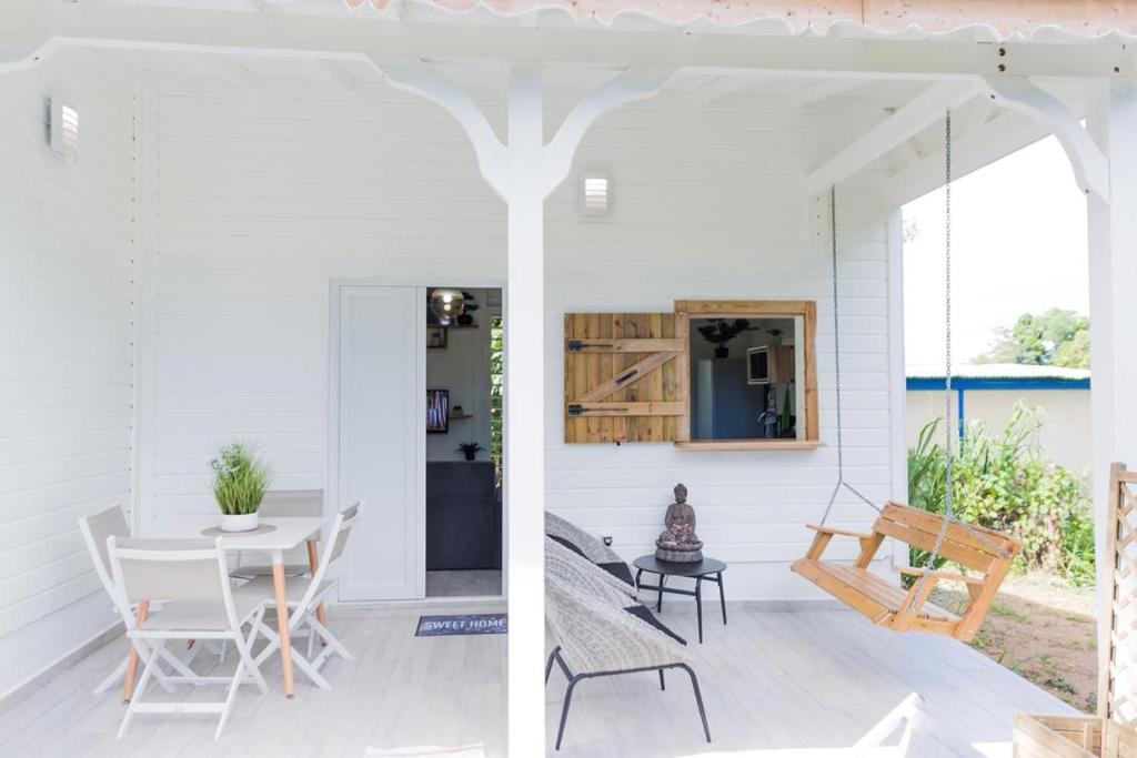 圣罗斯Sweety Paradise jacuzzi ,intimité zénitude et plages的白色的房子,设有门廊,配有桌子和椅子