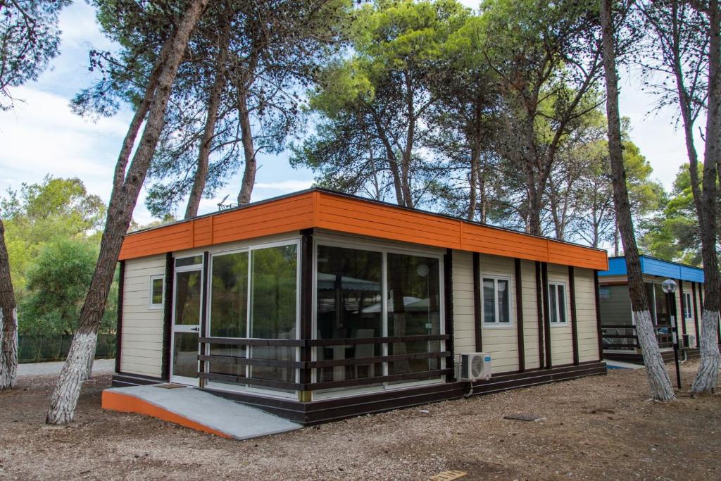波利科罗Policoro Village Hotel的树林里有一个橙色屋顶的小房子