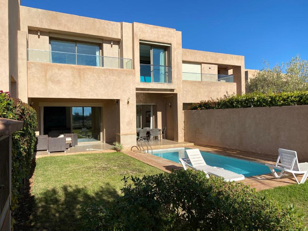 马拉喀什Villa prestige的一座带游泳池和两把草坪椅的房屋