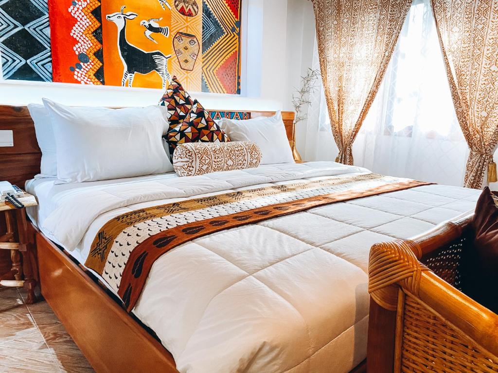 库马西Ike's Cultural Village的卧室配有一张带白色床单和枕头的大床。