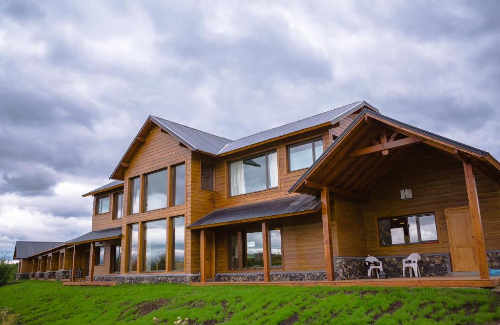 特来凡林Lago Rosario Lodge的绿色田野上带窗户的大型木制房屋