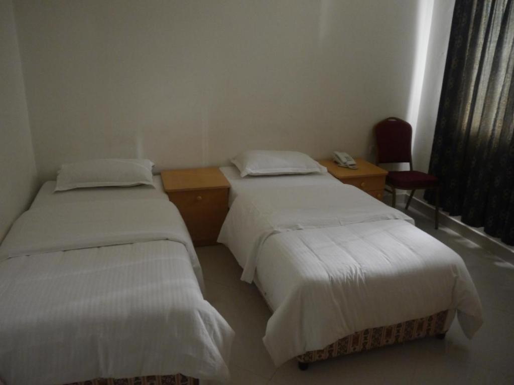 马斯喀特广场酒店的客房设有两张床、一张桌子和一把椅子。