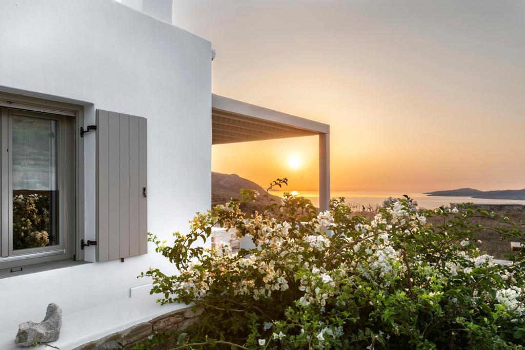 SteníWhite Tinos Luxury Suites的透过房子的窗户看到的日落