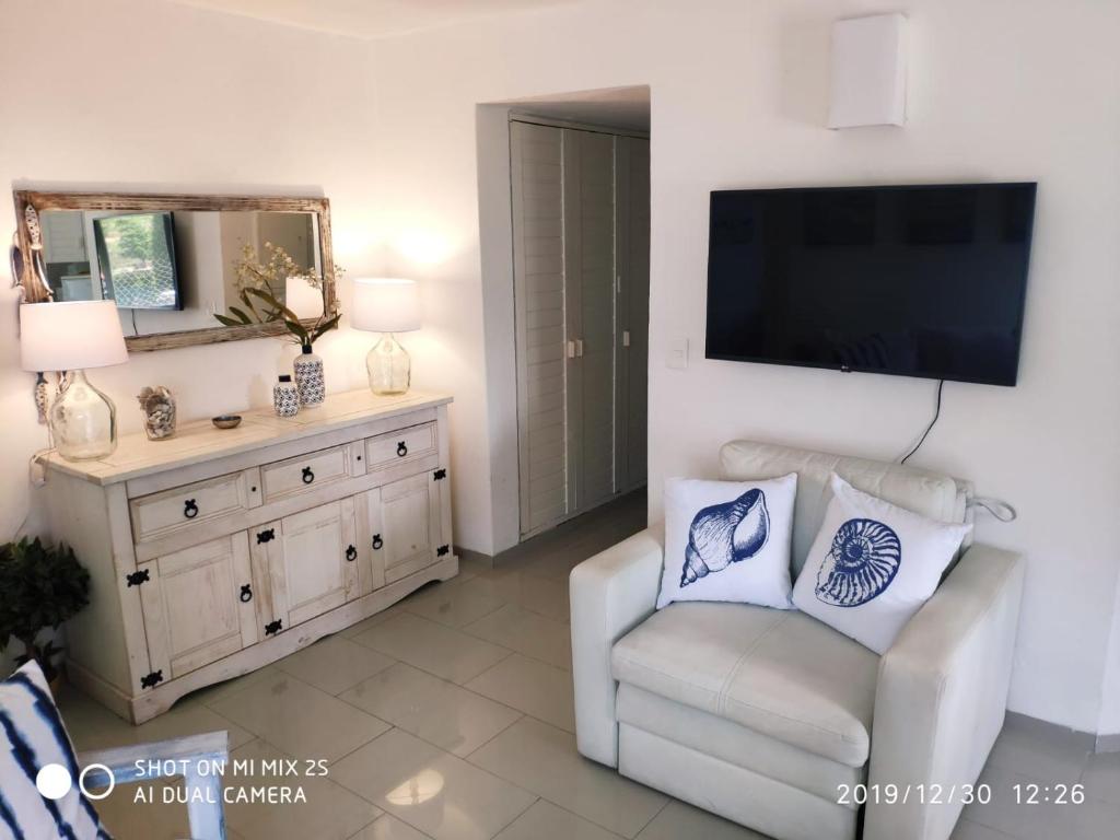 埃斯特角城Apartamento Marina de roosvelt con piscina climatizada的客厅配有白色椅子和平面电视