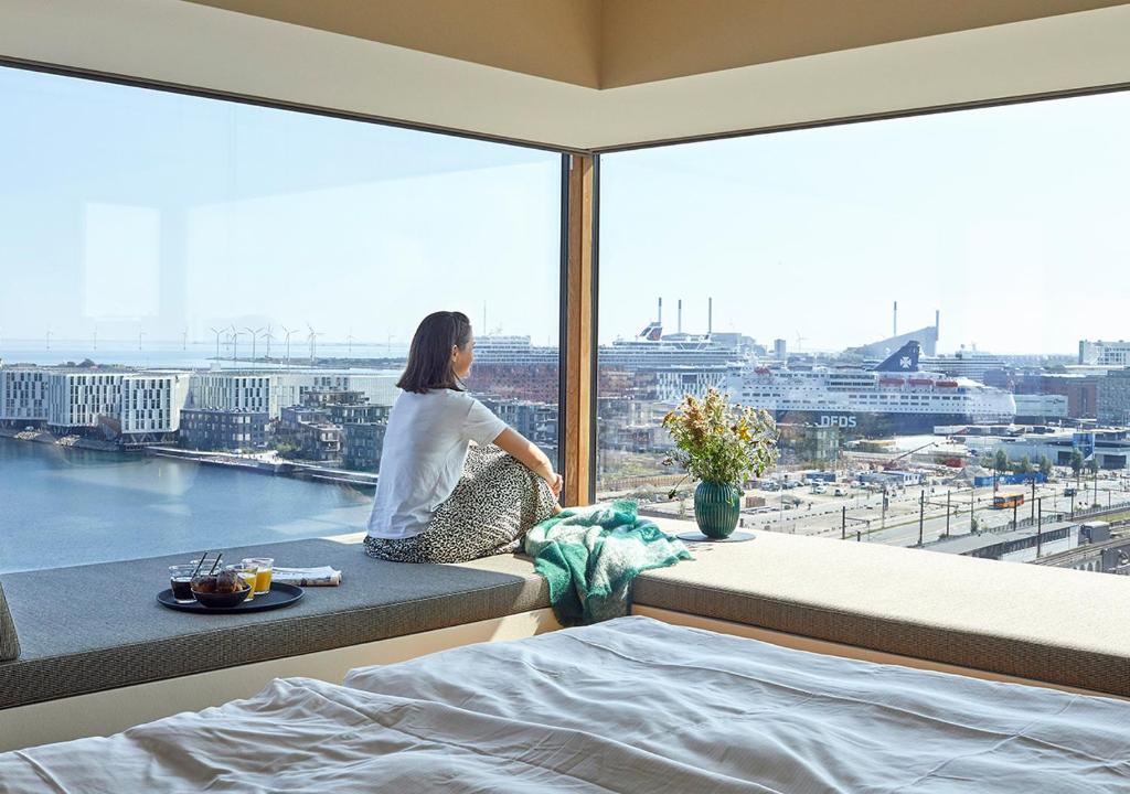 哥本哈根Charlottehaven的坐在靠窗座位上,望着城市的女人