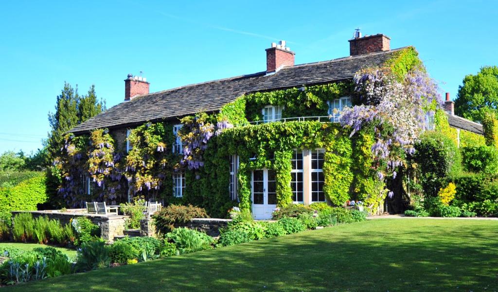 麦克尔斯菲尔德Hilltop Country House的常春藤覆盖的房子,前面有一个花园