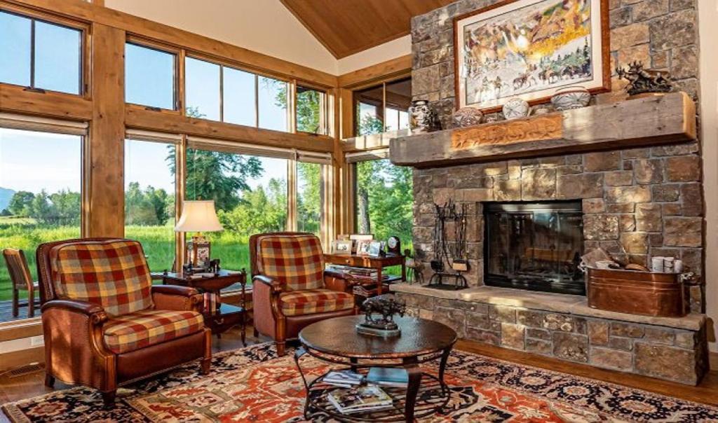 杰克逊Teton View Cabin的客厅设有石制壁炉和椅子